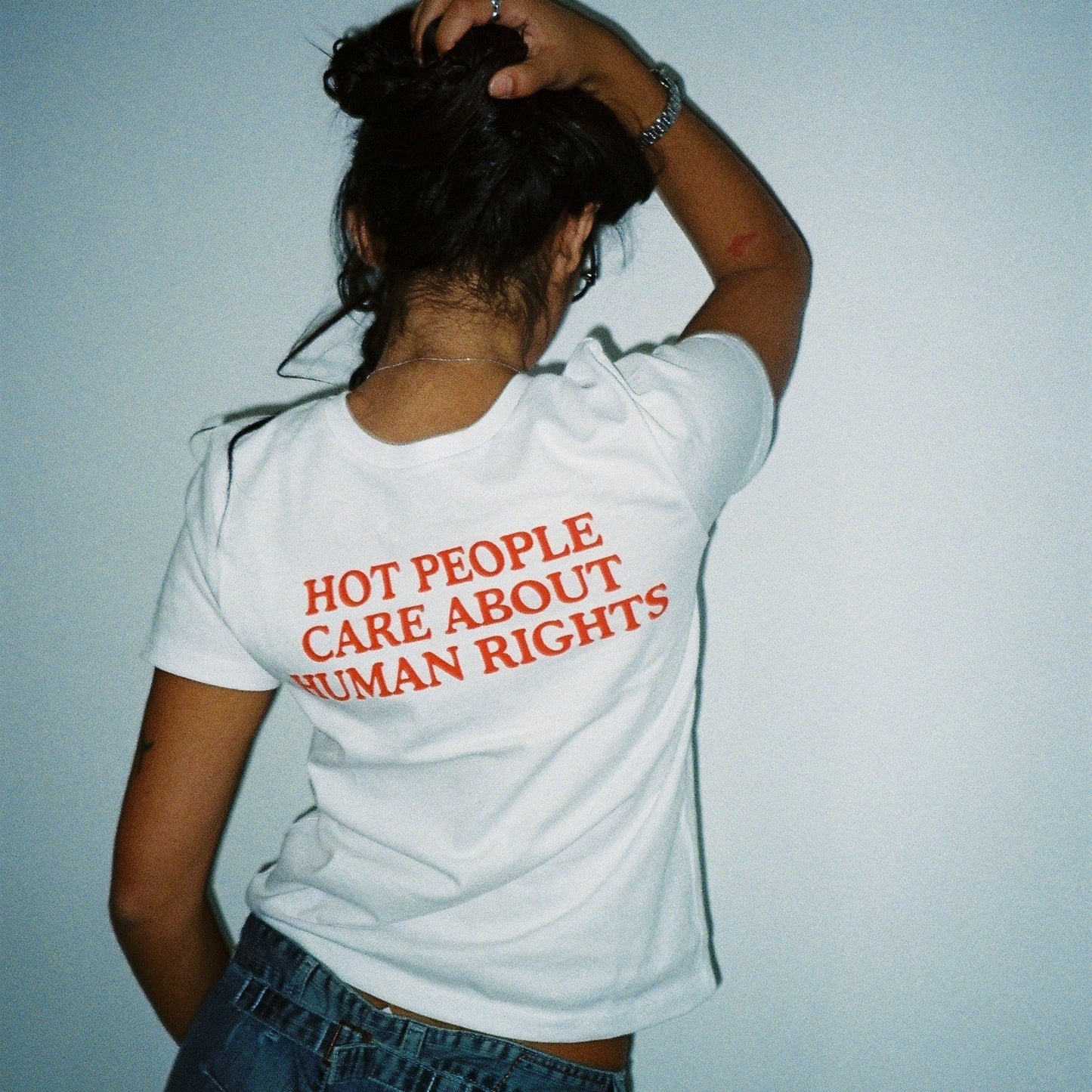 Person wearing a white t-shirt with red text against a light blue background