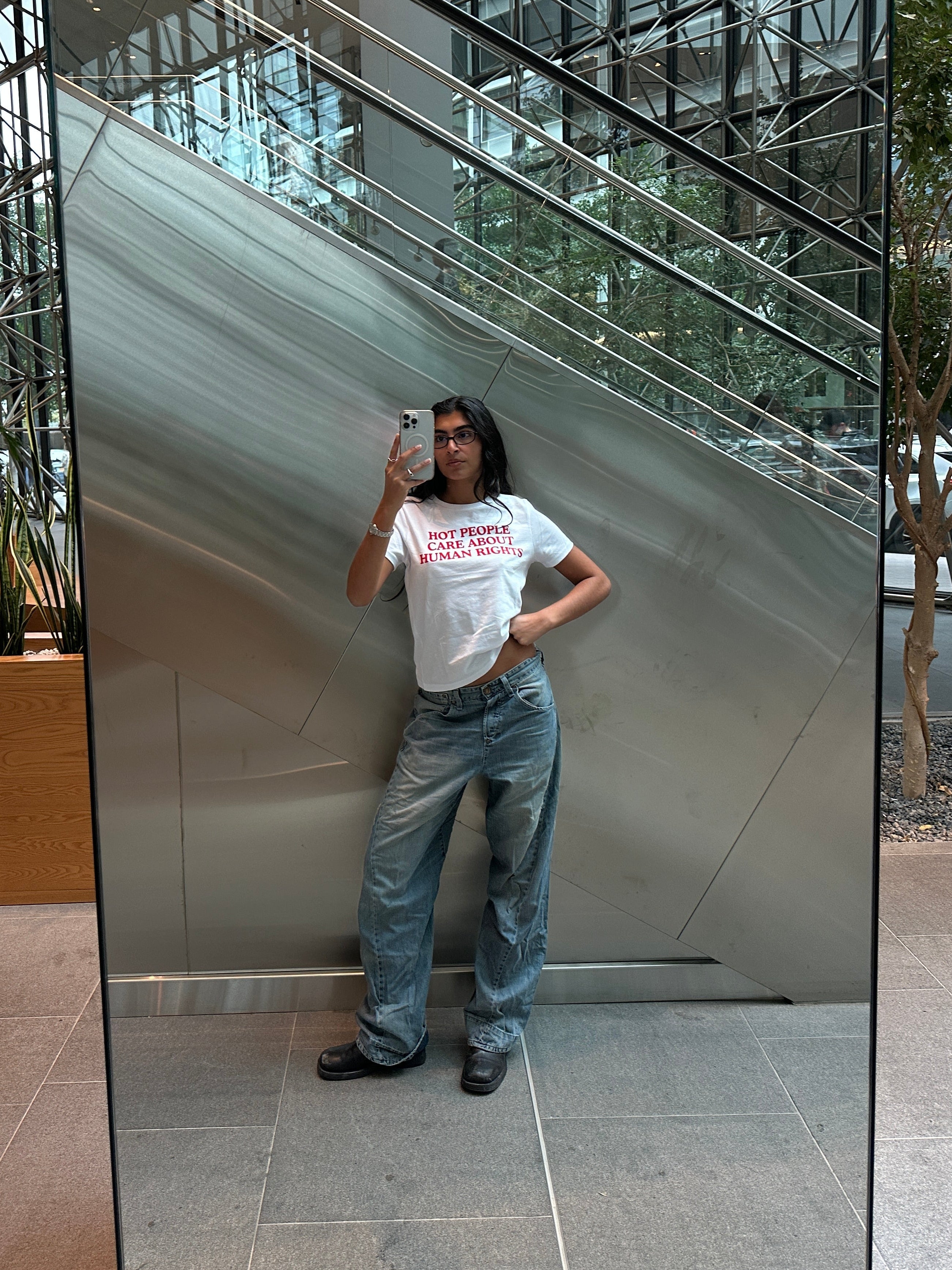 Person taking a selfie in front of a large mirror inside a building.